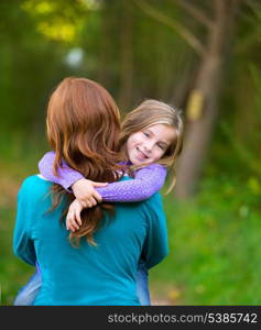 Mum holding daughter kid girl in her arms rear view smiling in outdoor