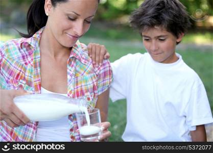 Mum pouring out a glass of milk for her son