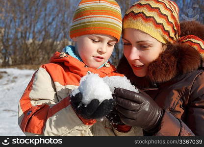 Mum with the son play with snow outdoor