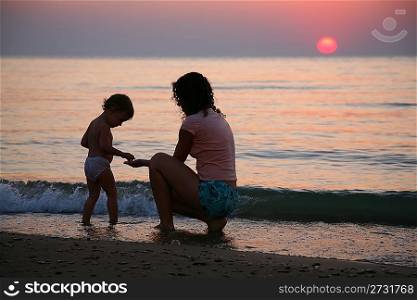 Mummy with the child ashore of sea on sunset