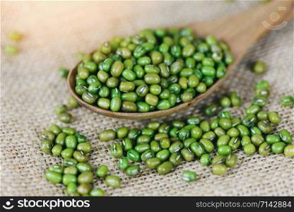 Mung beans in wooden spoon on the sack background / Close up green mung bean seed cereal whole grains
