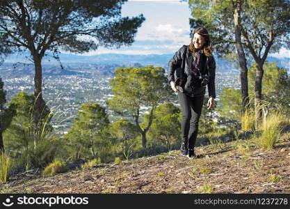Murcia, Spain - April 9, 2019: cheerful young woman hiking and taking pictures with her reflex camera. Murcia, Spain - April 9, 2019: cheerful young woman hiking and taking pictures with her reflex