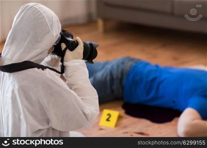 murder, investigation, forensic examination and people concept - criminalist with camera photographing dead male victim body at crime scene. criminalist photographing dead body at crime scene