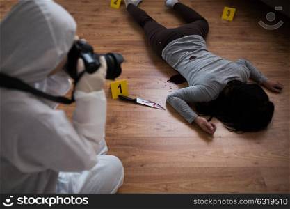 murder, investigation, forensic examination and people concept - criminalist with camera photographing dead female victim body at crime scene. criminalist photographing dead body at crime scene