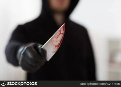 murder, kill and people concept - close up of criminal or murderer with blood on knife at crime scene. close up of criminal with blood on knife