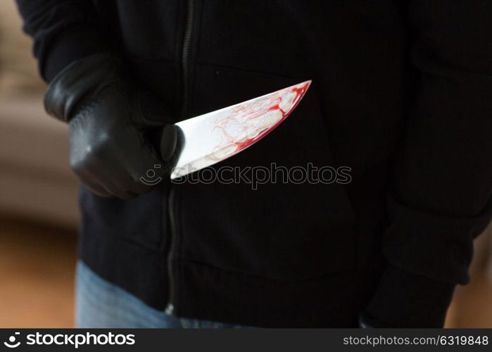 murder, kill and people concept - close up of criminal or murderer with blood on knife at crime scene. close up of criminal with blood on knife