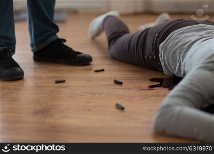 murder, kill and people concept - criminal or murderer with bleeding dead woman body lying on floor and bullet sleeves at crime scene. criminal with dead body and bullets at crime scene