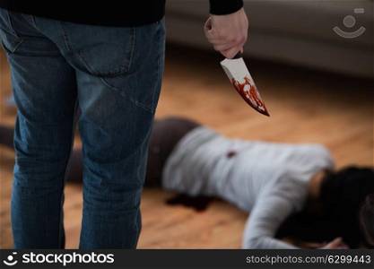 murder, kill and people concept - criminal or murderer with knife in blood and dead woman body lying on floor at crime scene. criminal with knife and dead body at crime scene