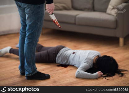 murder, kill and people concept - criminal or murderer with knife in blood and dead woman body lying on floor at crime scene (staged photo). criminal with knife and dead body at crime scene
