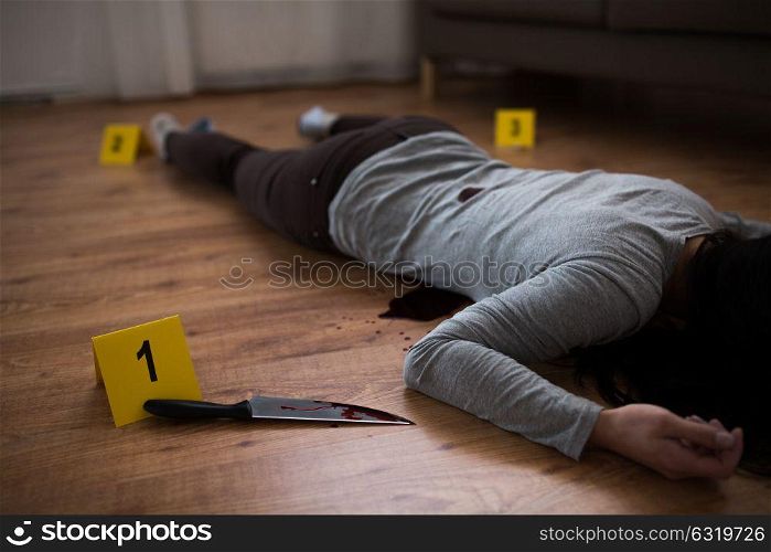 murder, kill and people concept - dead woman body and knife in blood lying on floor at crime scene. dead woman body lying on floor at crime scene