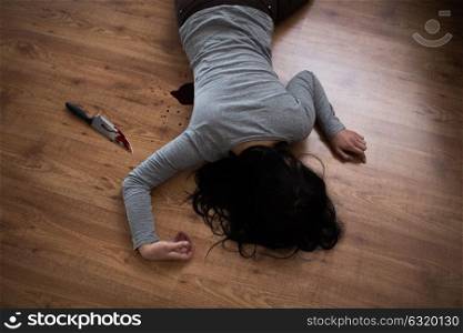 murder, kill and people concept - dead woman body and knife in blood lying on floor at crime scene (staged photo). dead woman body lying on floor at crime scene