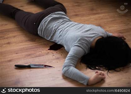 murder, kill and people concept - dead woman body and knife in blood lying on floor at crime scene (staged photo). dead woman body lying on floor at crime scene. dead woman body lying on floor at crime scene