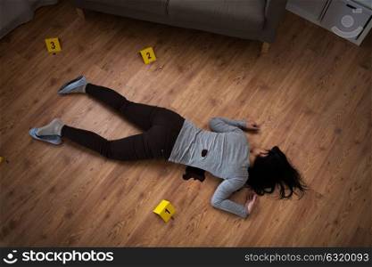 murder, kill and people concept - dead woman body in blood lying on floor and bullet sleeves at crime scene (staged photo). dead woman body in blood on floor at crime scene