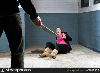 Murderer, holding a knife, face to face with a terrified woman in a basement