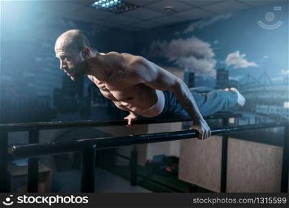 Muscle athlete makes horizontal balance exercises on gymnastic bars in gym. Strong gymnast on training