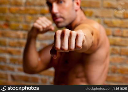 muscle boxer shaped man fist to camera on brickwall