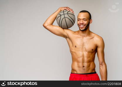 Muscular african american sportsman playing basketball shitless over light grey background.. Muscular african american sportsman playing basketball shitless over light grey background