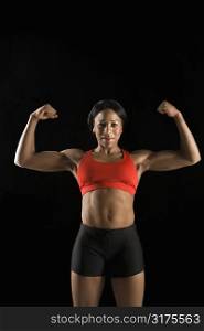 Muscular African American woman wearing athletic apparel with biceps flexed.