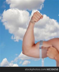 Muscular arm of a man's biceps measure yourself against a blue sky