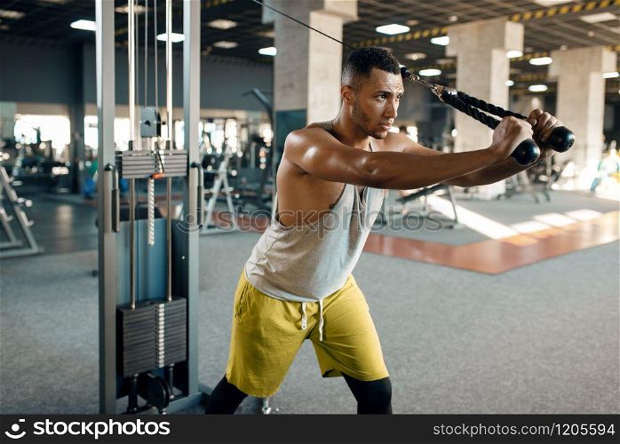 Muscular athlete in sportswear at exercise machine in motion on training in gym. Workout in sport club, healthy lifestyle. Athlete at exercise machine in motion, sport club