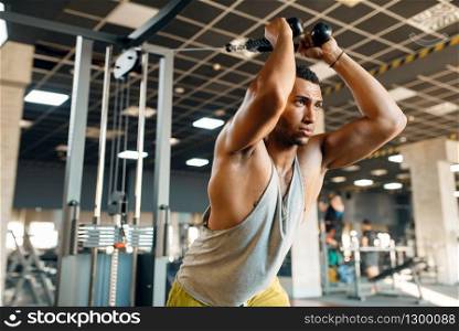 Muscular athlete in sportswear at exercise machine in motion on training in gym. Workout in sport club, healthy lifestyle