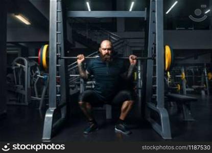 Muscular athlete in sportswear doing exercise with barbell, training in gym. Bearded man on workout in sport club, healthy lifestyle. Muscular athlete doing exercise with barbell