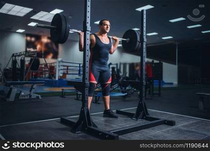 Muscular athlete prepares to make squats with barbell in gym. Weightlifting workout, powerlifting training. Athlete prepares to make squats with barbell