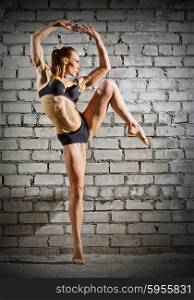 Muscular dancing woman on grey brick wall (normal version)