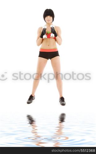 muscular fitness instructor with dumbbells on white sand