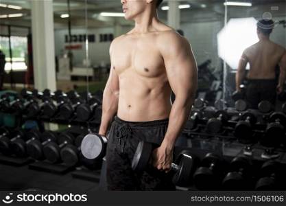 Muscular fitness man bodybuilder is workout with dumbbells in gym