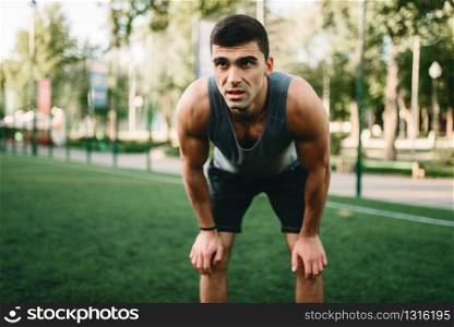 Muscular male athlete prepares for the training, fitness workout. Strong sportsman in park. Muscular male athlete prepares for the training