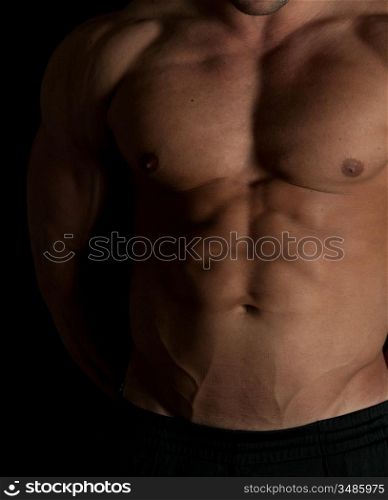 Muscular male torso of bodybuilder on black background