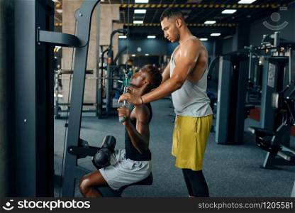 Muscular man and his instructor, exercise with barbell on training in gym. Workout in sport club, healthy lifestyle. Muscular man and his instructor, training in gym