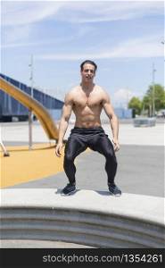 Muscular man doing box jumps outdoors.
