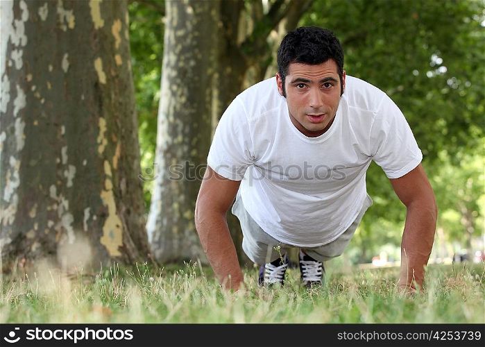 muscular man doing push-ups in a park