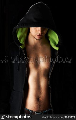 Muscular man in hoodie over black background