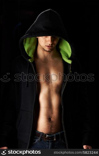 Muscular man in hoodie over black background
