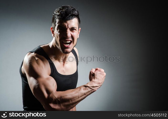 Muscular man posing in dark studio