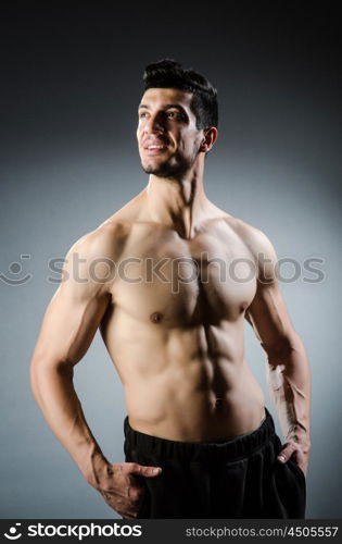 Muscular man posing in dark studio