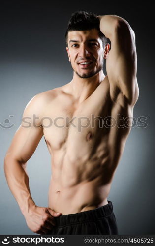 Muscular man posing in dark studio