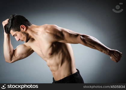 Muscular man posing in dark studio