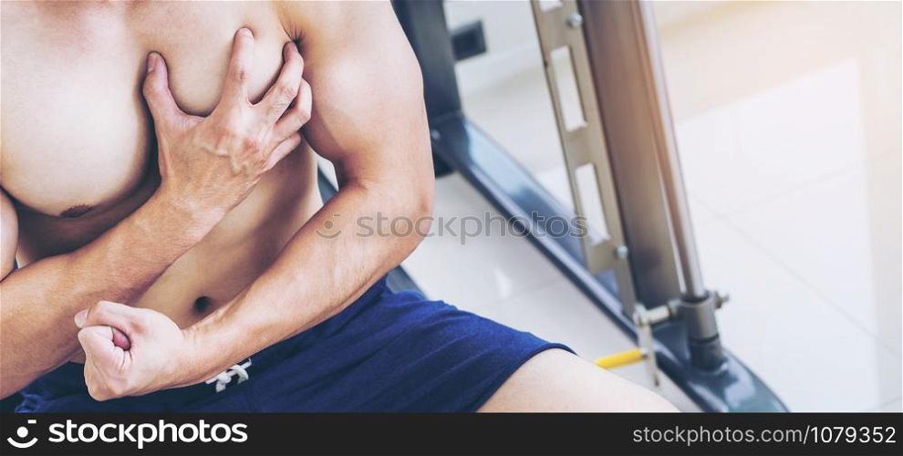 Muscular man touching his chest in fitness center. Bodybuilding concept.
