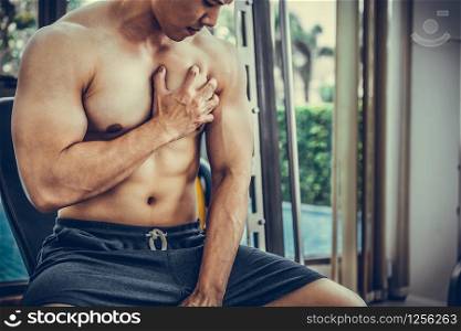 Muscular man touching his chest in fitness center. Bodybuilding concept.