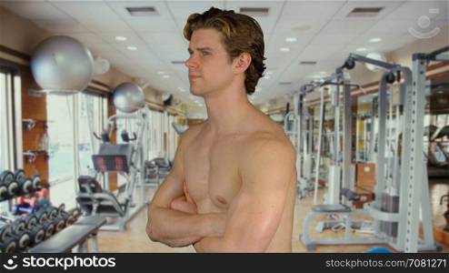 Muscular man with arms crossed in a gym