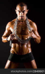 Muscular man with chain on black background