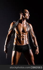 Muscular man with chain on black background