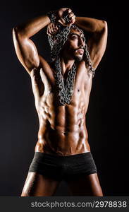 Muscular man with chain on black background