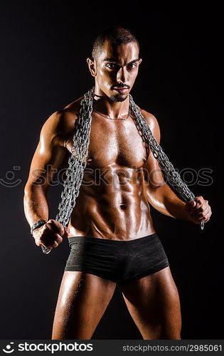 Muscular man with chain on black background