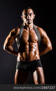 Muscular man with chain on black background