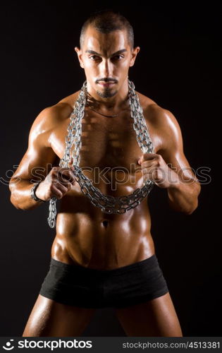 Muscular man with chain on black background